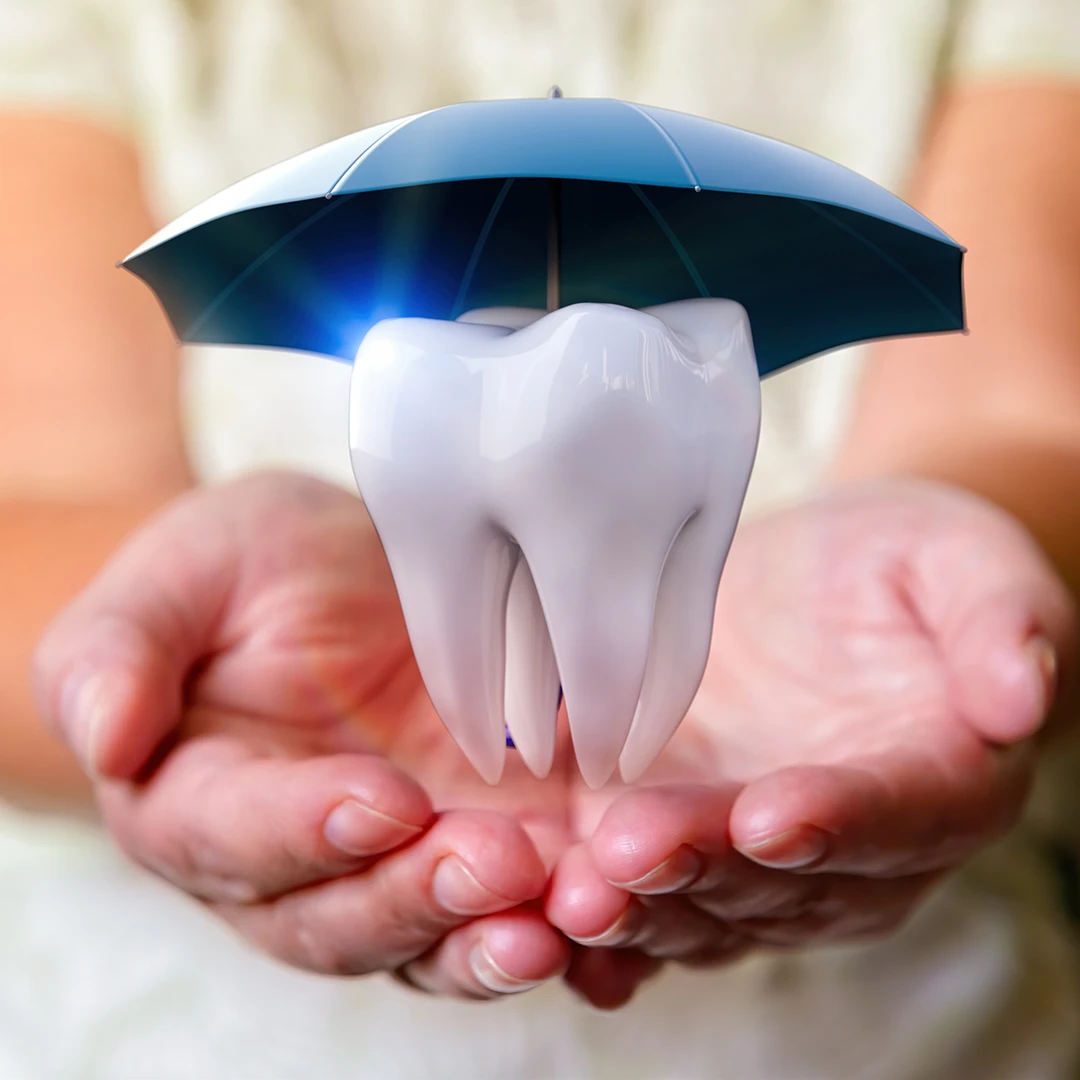 Hands holding tooth protected by umbrella